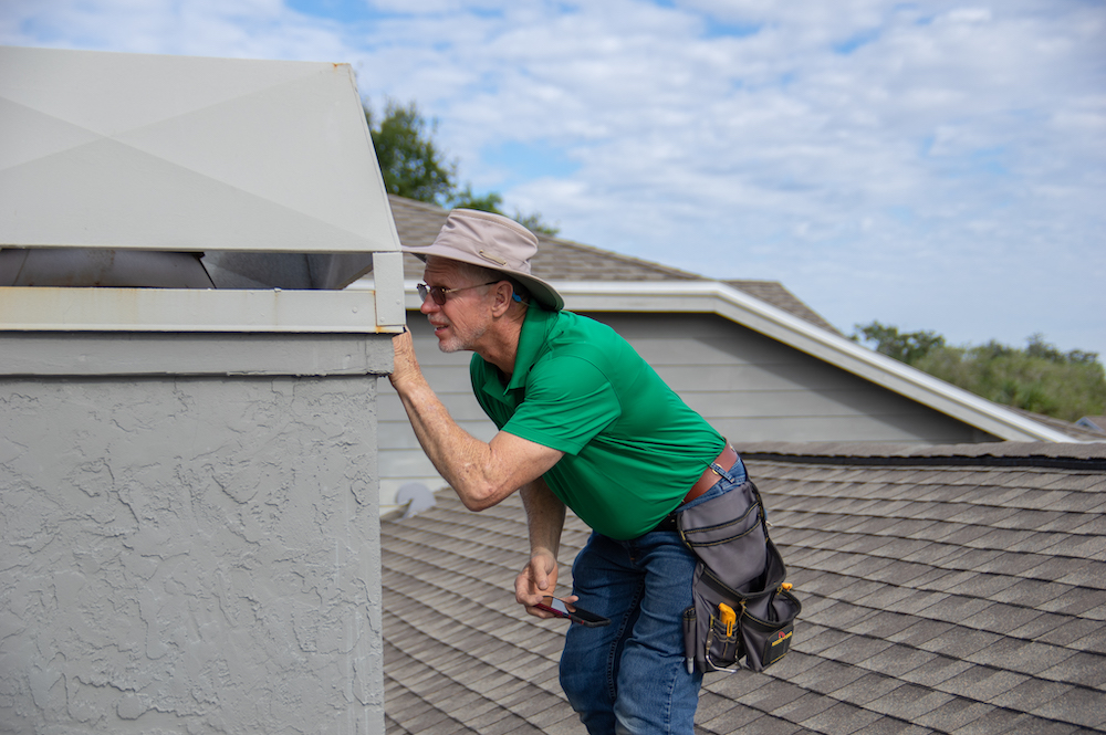 Inspector on roof inspecting chimney